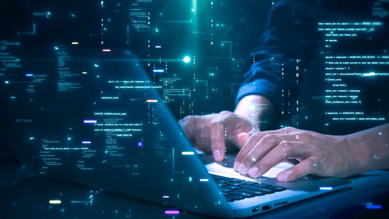 Close-up of hands typing on a laptop with glowing programming code and binary graphics